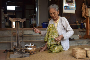 Grandma making thread from cotton on a spinning wheel
